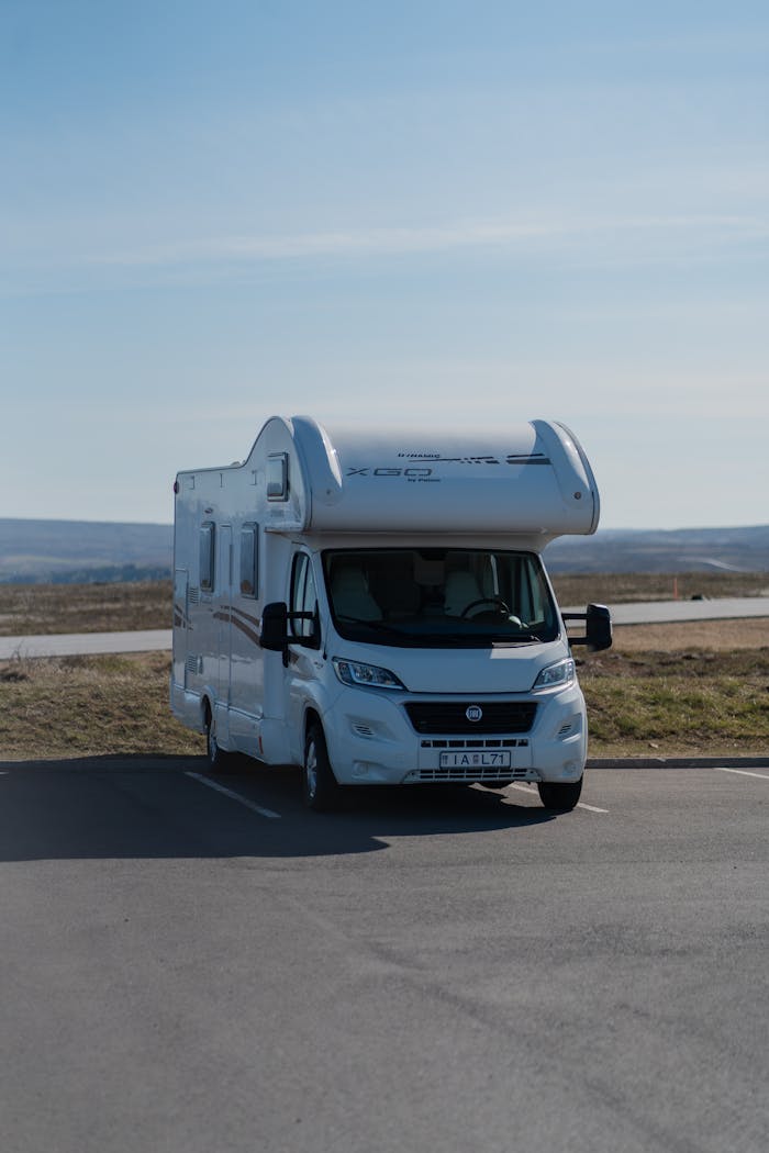 A camper van parked on an empty lot with a scenic valley backdrop under clear skies.